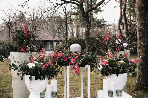 Dekoration im Freien mit roten Blumen und weißen Vasen