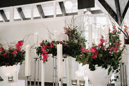 Eine Dekoration mit roten Blumen, weißen Vasen und Kerzen in der Trauerhalle